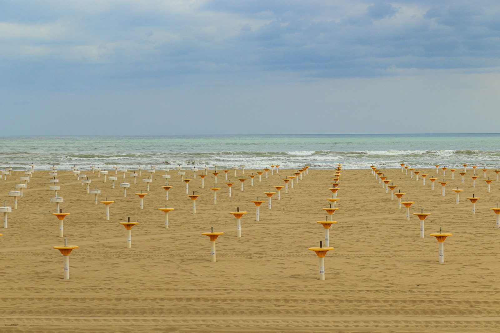 Rows of closed parasols on an empty beach out of season.