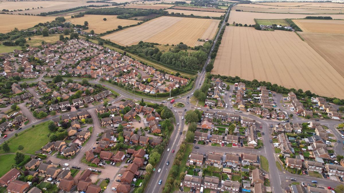 A high, wide aerial view of a town and the farmland around it, where nobody is identifiable.