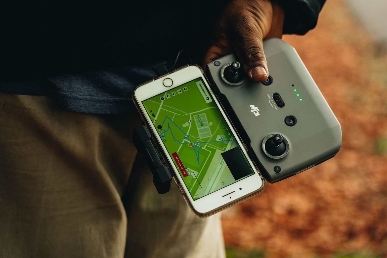 A phone showing an airspace map, clipped to a drone controller held outdoors.