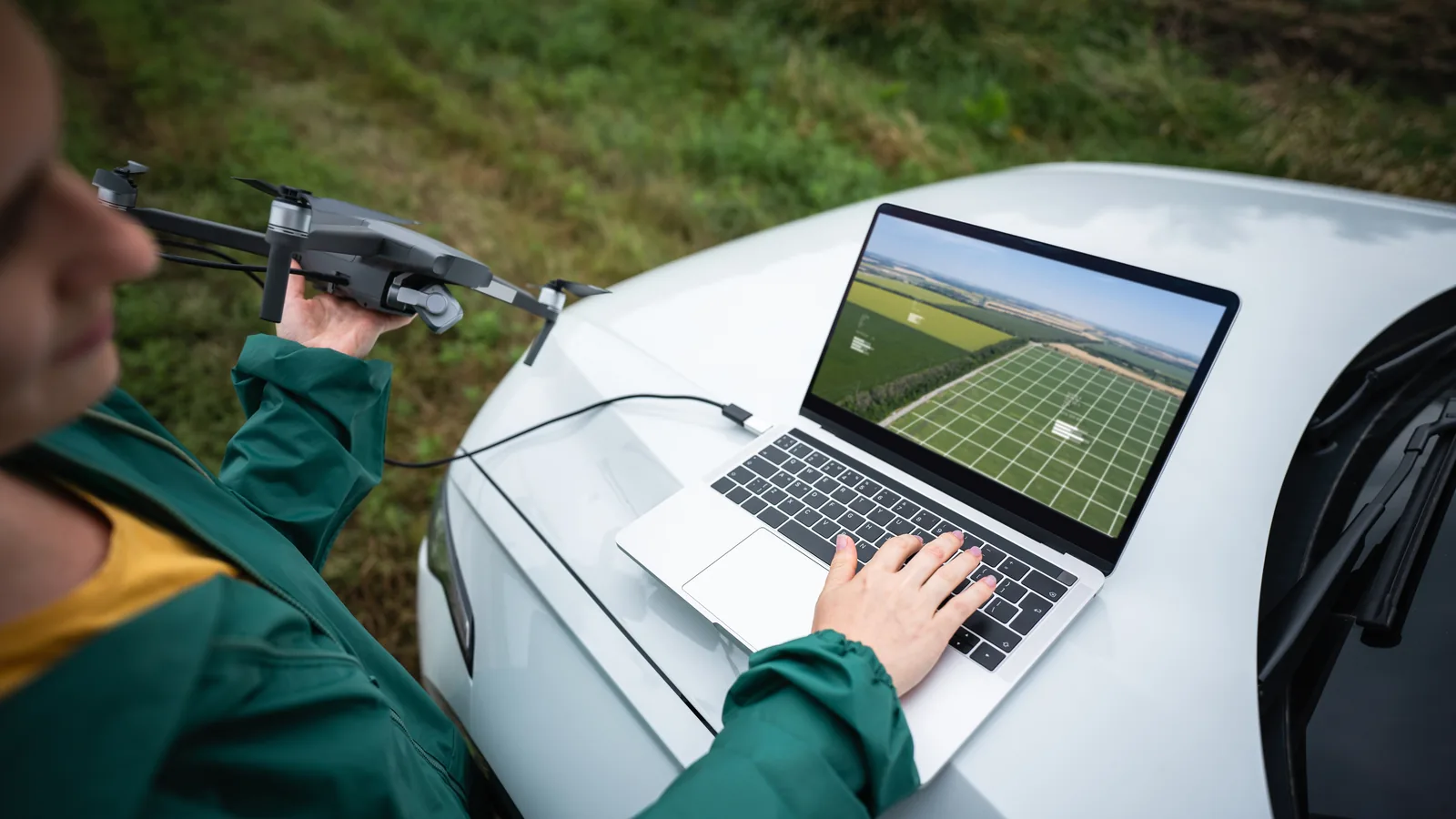Drone operator reviewing aerial mapping data on a laptop beside the aircraft.
