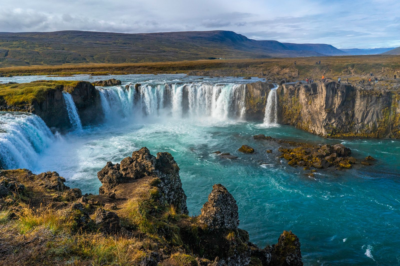 Goðafoss waterfall cascading across dark volcanic rock in northern Iceland.