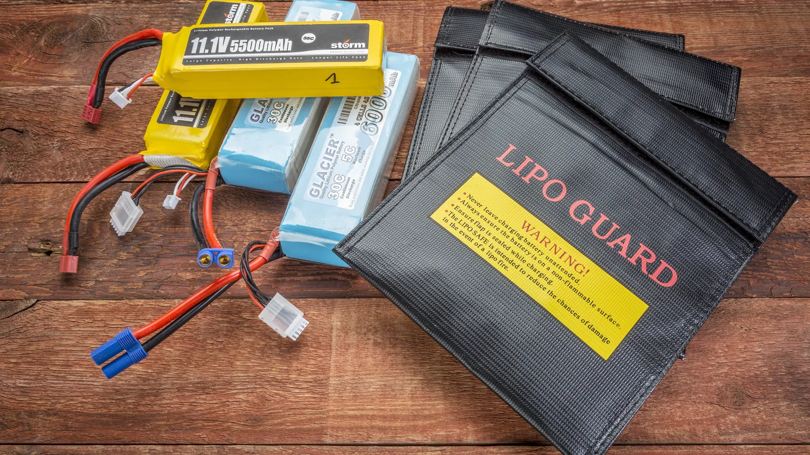 Lithium-polymer drone batteries arranged beside fire-resistant battery storage bags.