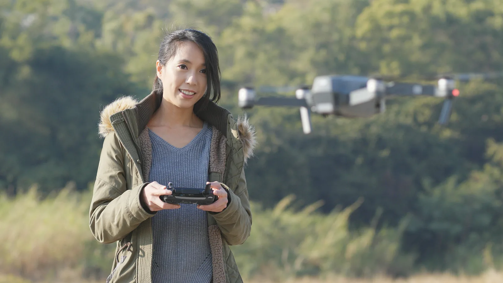 Recreational drone pilot flying a compact camera drone in an open rural area.