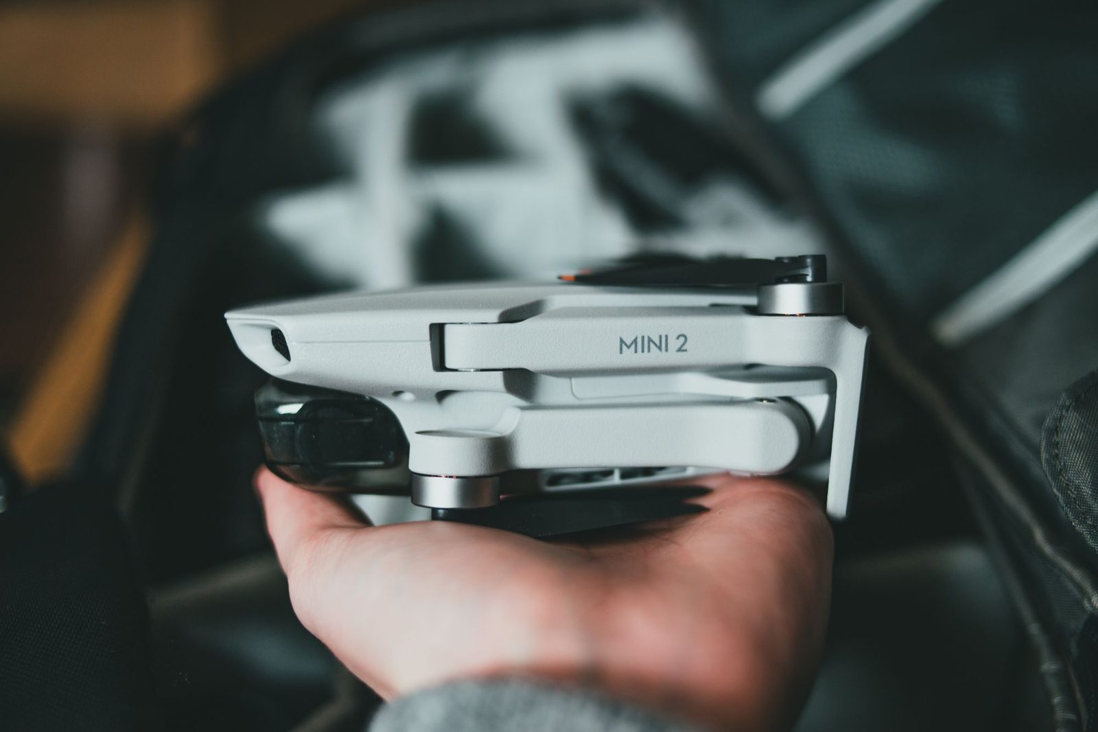 A hand holding a compact folding camera drone with its arms extended.