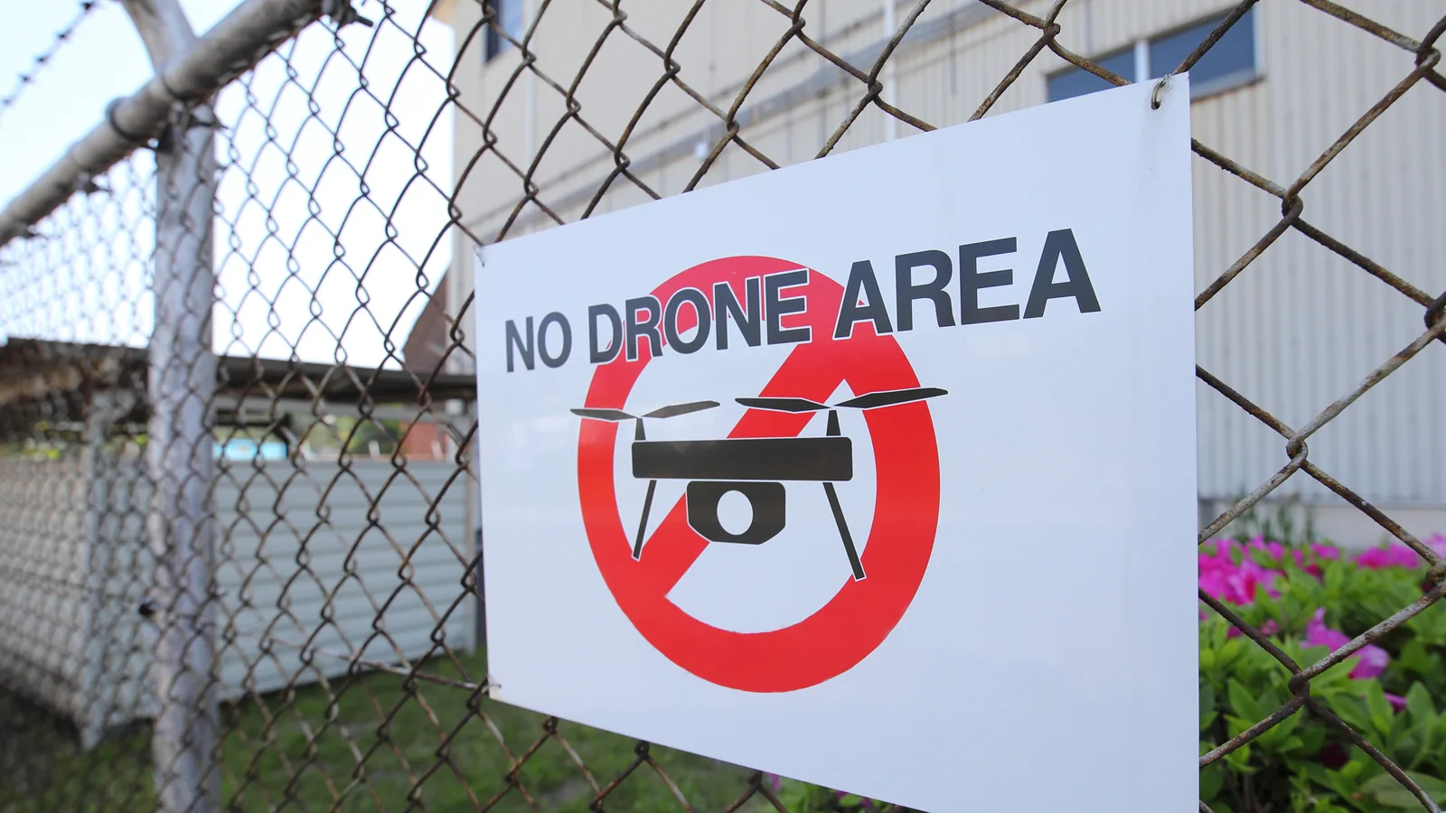 No-drone-area sign attached to a secured industrial perimeter fence.