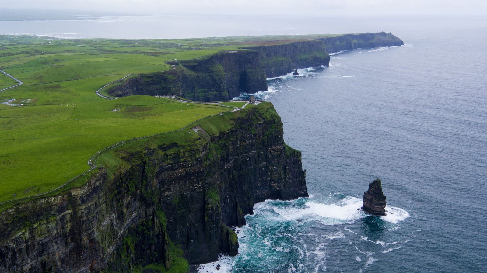An aerial view along the Cliffs of Moher, with the sea stack standing at their foot.