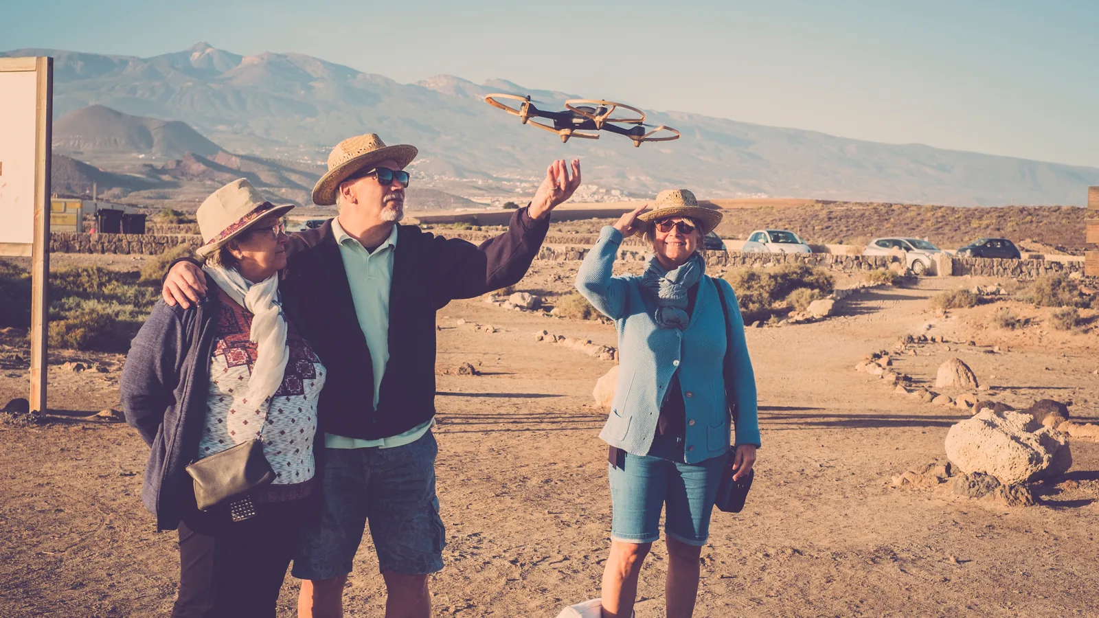 Tourists standing close together while one person launches a small drone by hand.