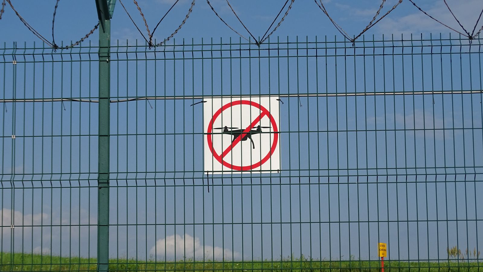 No-drone sign on a secured perimeter fence