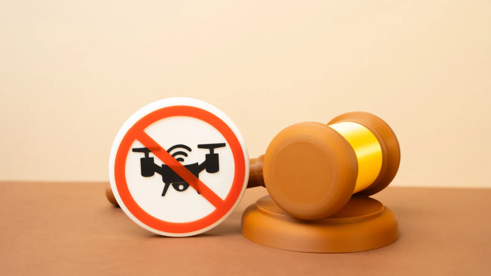 No-drone symbol beside a judge’s gavel representing enforcement and penalties