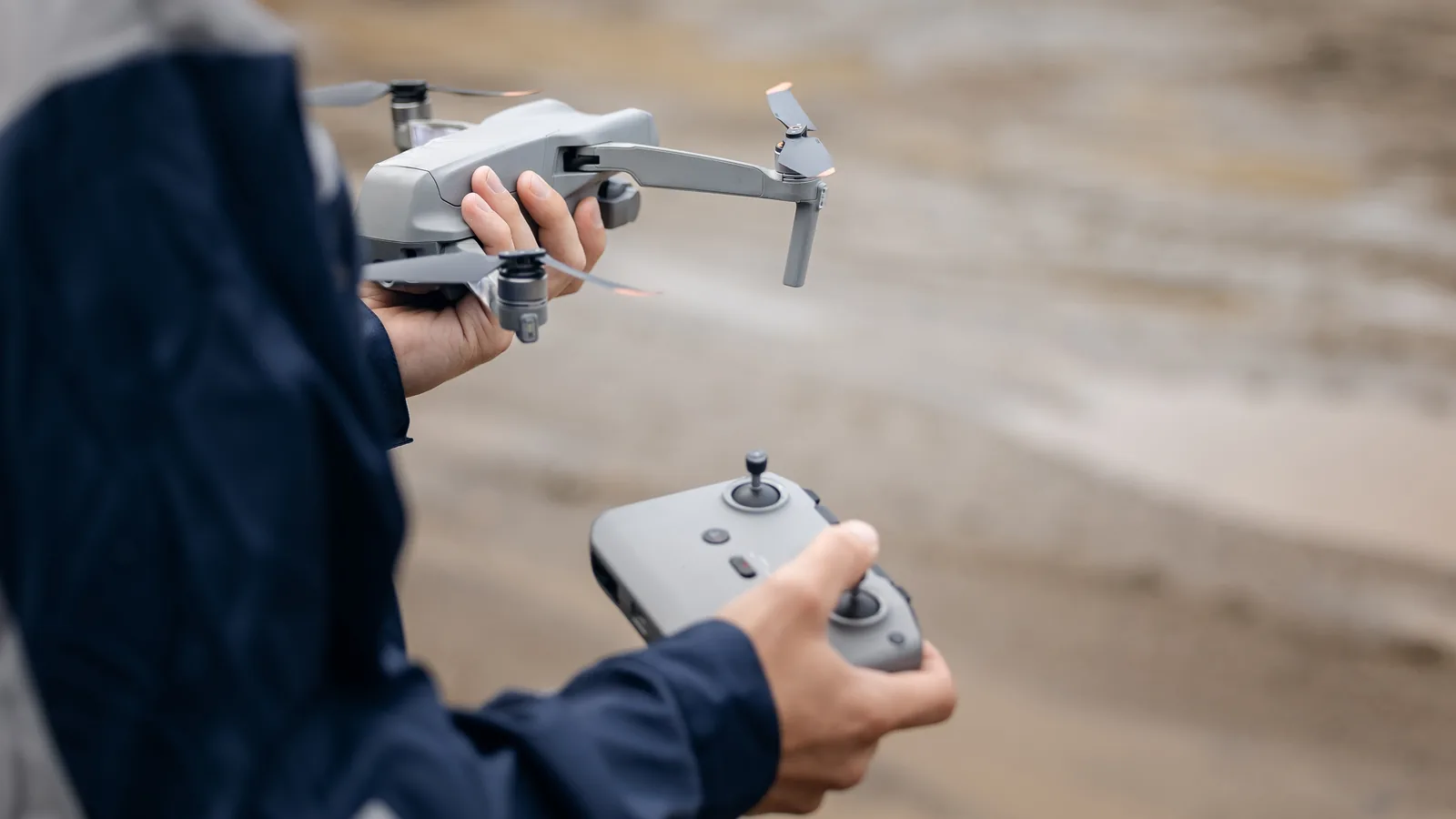Drone operator holding a camera drone and its remote controller before registration