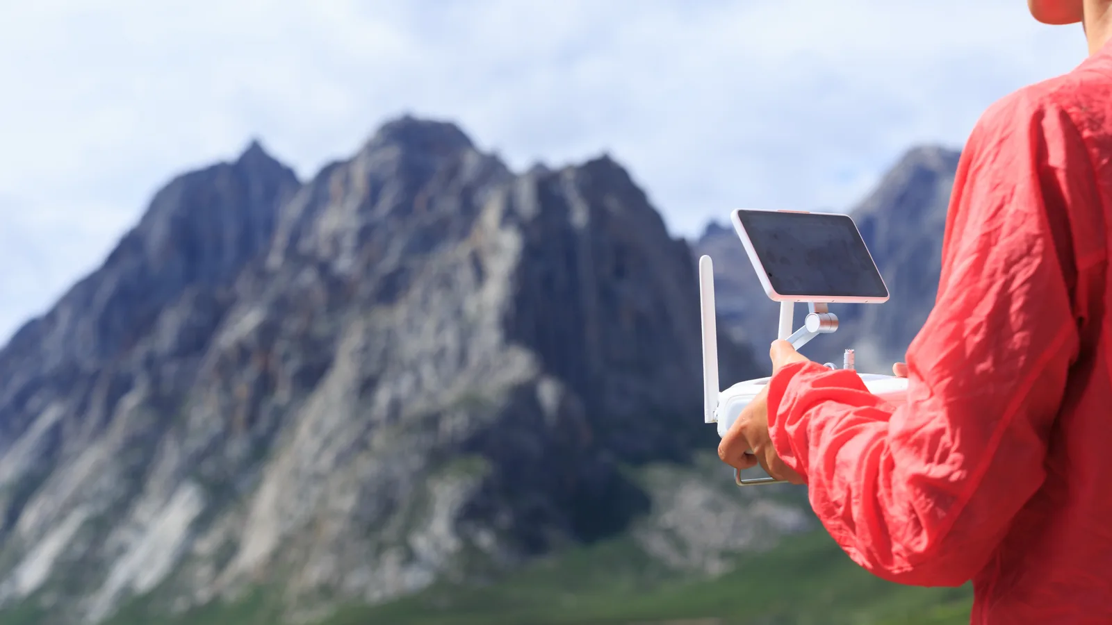 Drone pilot checking a controller screen while planning a mountain flight