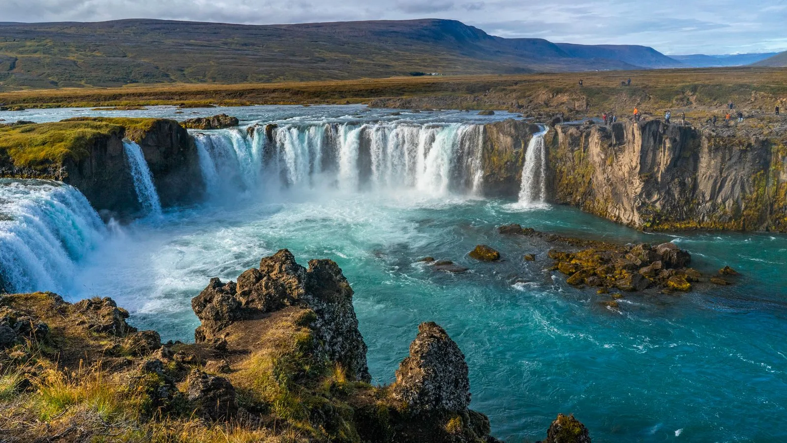 Goðafoss waterfall cascading across dark volcanic rock in northern Iceland.
