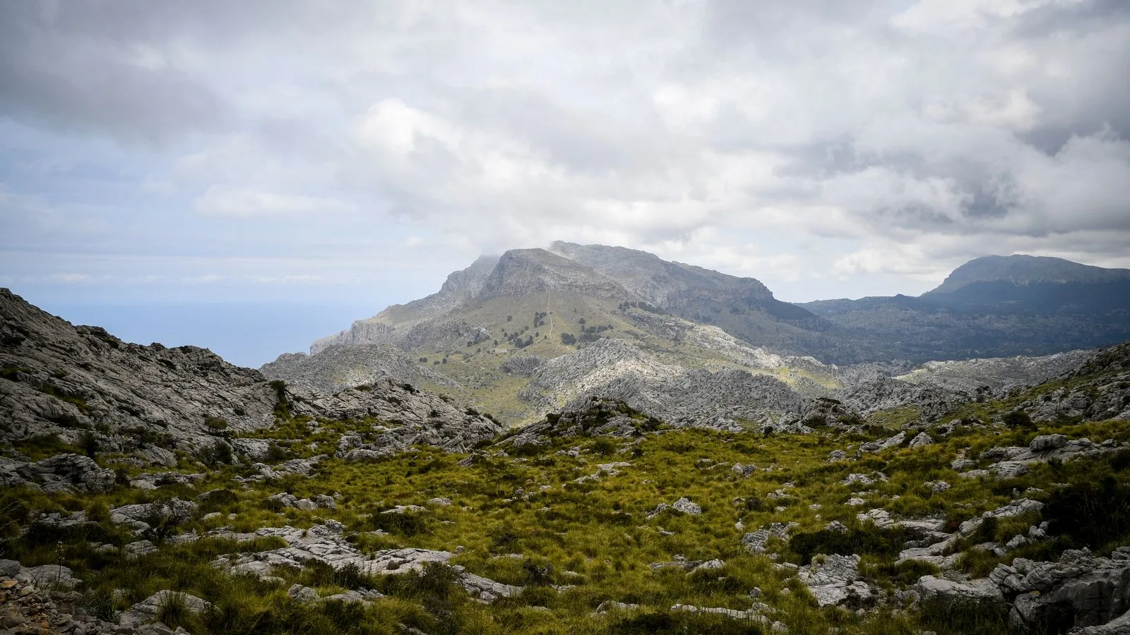 Rugged limestone ridges in Serra de Tramuntana, Mallorca, beneath a cloudy sky.